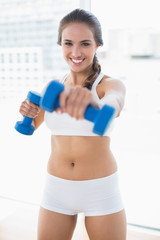 Happy sporty brunette using dumbbells