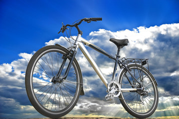 Fototapeta na wymiar Rower sportowy na tle nieba, chmur i promieni słonecznych.