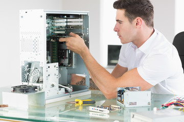 Handsome unsmiling computer engineer working at open computer