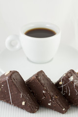Three chocolate cakes with cup of black tea on white background