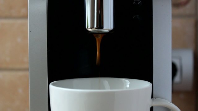 Kaffee l&auml;uft durch Kaffeeautomat in Tasse