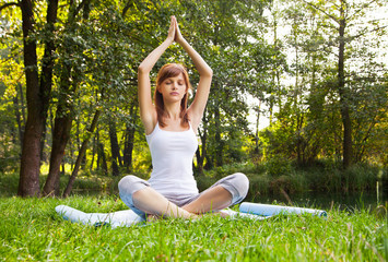 Young girl doing yoga (lotus pose) in the park