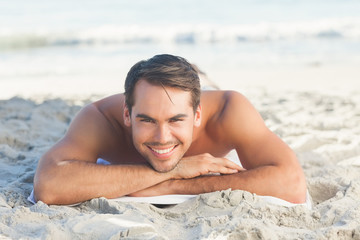 Smiling handsome man on the beach lying on his towel