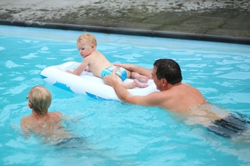 Happy father with son and baby daughter swimming in pool