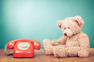Retro red telephone and Teddy Bear near mint green wall