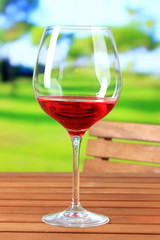 Glasses of wine on wooden table on nature background