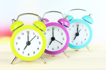 Colorful alarm clocks on table on light background