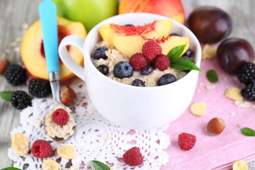 Oatmeal in cup with berries on napkins on wooden table