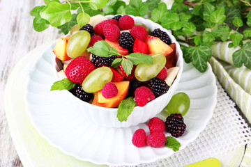 Fruit salad in bowl, on wooden table background