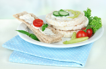 Tasty crispbreads with vegetables on white table