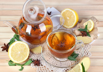 Kettle and cup of tea with ginger on napkin on wooden table