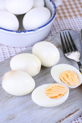Boiled eggs on wooden board on tablecloth