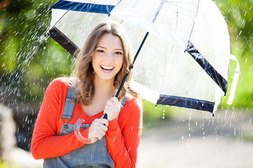 Beautiful young woman holding umbrella out in the rain