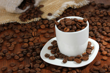 Coffee beans in cup on wooden background