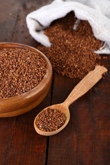 Buckwheat groats in bowl and  wooden spoon closeup