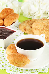 Tasty croissants and cup of coffee on table close-up