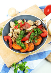 Sliced fresh vegetables in pan on wooden board isolated on