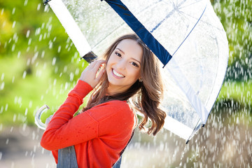 Beautiful young woman holding umbrella out in the rain