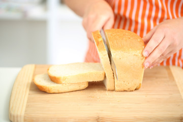 Woman slicing bread on chopping board, close up