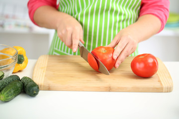 Happy smiling woman in kitchen  holding fresh vegetables in her