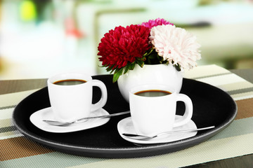 Cups of coffee on tray on table in cafe