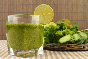 Glass of green vegetable juice and vegetables