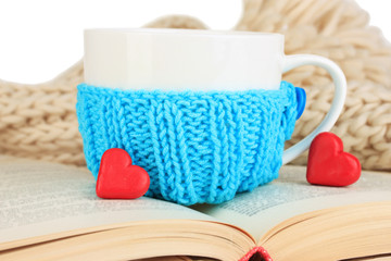 Obraz na płótnie Canvas Cup with knitted thing on it and open book close up