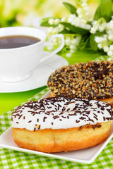 Sweet donuts with cup of tea on table on bright background