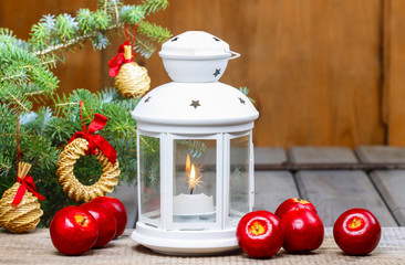 Beautiful white lantern on wooden table, red apples around