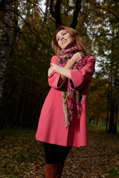 Beautiful woman in pink coat walks in the Park
