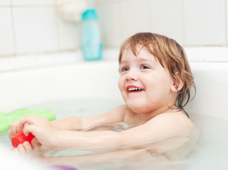  child bathes with toys in bathtub