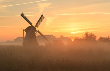 Windmill at foggy sunrise