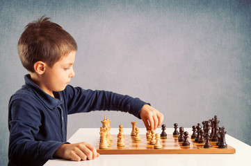 Kid playing chess on grunge background.
