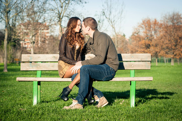 Fototapeta premium Happy young couple sitting outdoors on a bench.