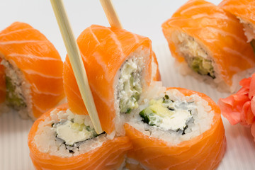 Philadelphia sushi roll with ginger and wasabi on white dish