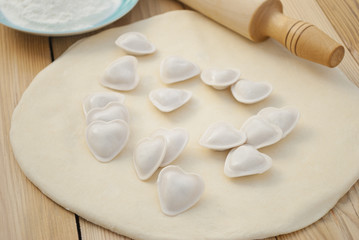 Fototapeta na wymiar Dumplings in a heart shape dough and rolling pin.