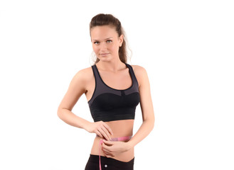 Obraz premium Fit girl measuring her waist with a measuring tape in inch