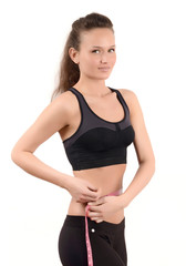 Fit girl measuring her waist with a measuring tape in inch