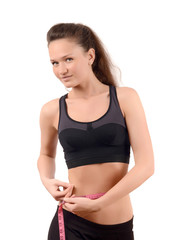 Girl measuring her waist with a measuring tape in centimeters