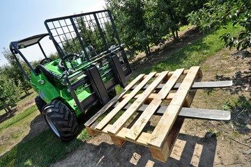 Green telescopic loader at work in the orchard.