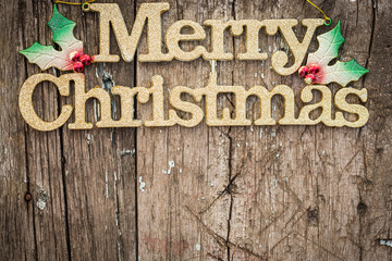 Gold text "Merry Christmas" on wood