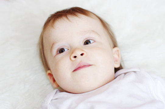 portrait of lovely baby lying on white bed