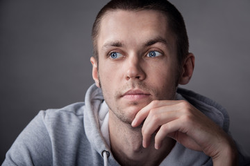 Closeup of young man with hand on head on gray background