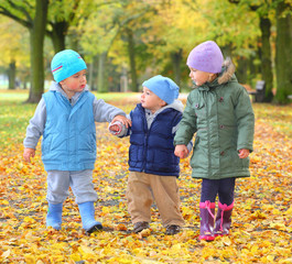 Funny kids playing in yellow foliage.  Autumn in the city park.