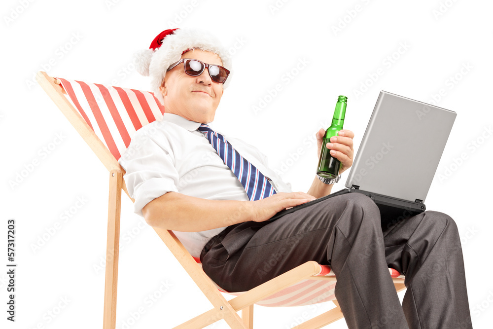 Wall mural Mature businessman with santa hat on a chair, drinking beer