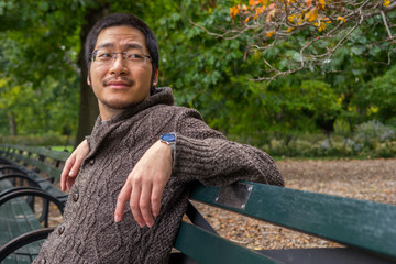 Asian man relaxing on a park bench