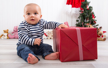 Baby mit einem Geschenk zu Weihnachten in Rot