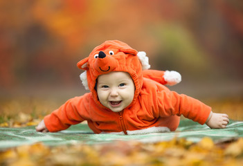 Laughing baby boy dressed in fox costume in autumn park