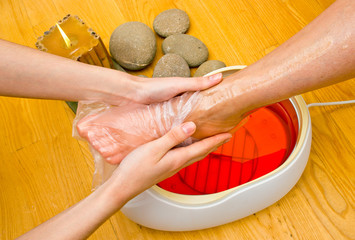 woman foot in paraffin bath at the spa - obrazy, fototapety, plakaty