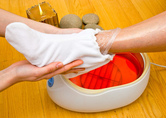 woman foot in paraffin bath at the spa